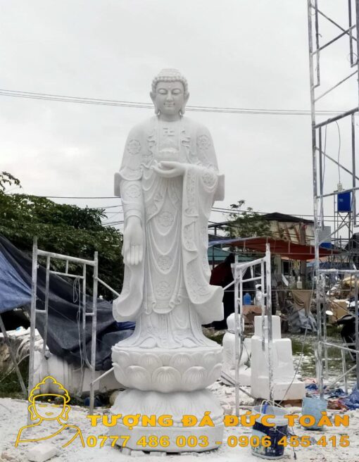 Tượng Phật A Di Đà Đá Non Nước màu trắng ở phía trước một công trường xây dựng.