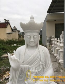 Tượng Địa Tạng Bồ Tát ngồi đá đẹp trước một tòa nhà.