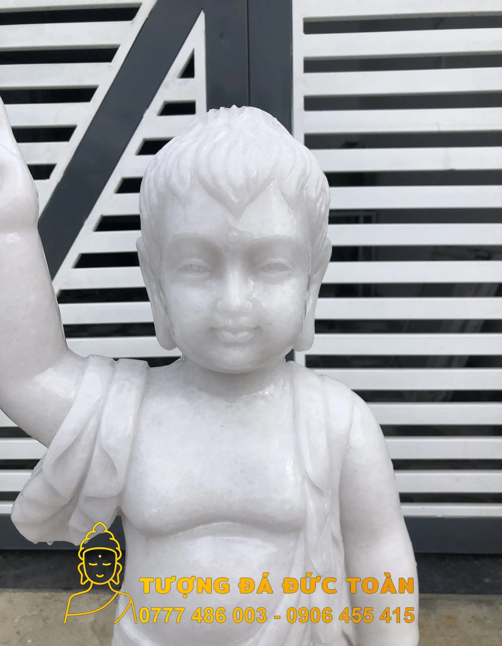 Tượng Phật Đản Sanh đá nguyên khối cúng Đường màu trắng trước cửa.