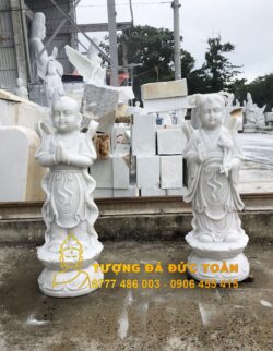 Hai tượng Bán tượng Thiện Tài Đồng Tử đá đẹp Đà Nẵng màu trắng trước một tòa nhà ở Đà Nẵng.