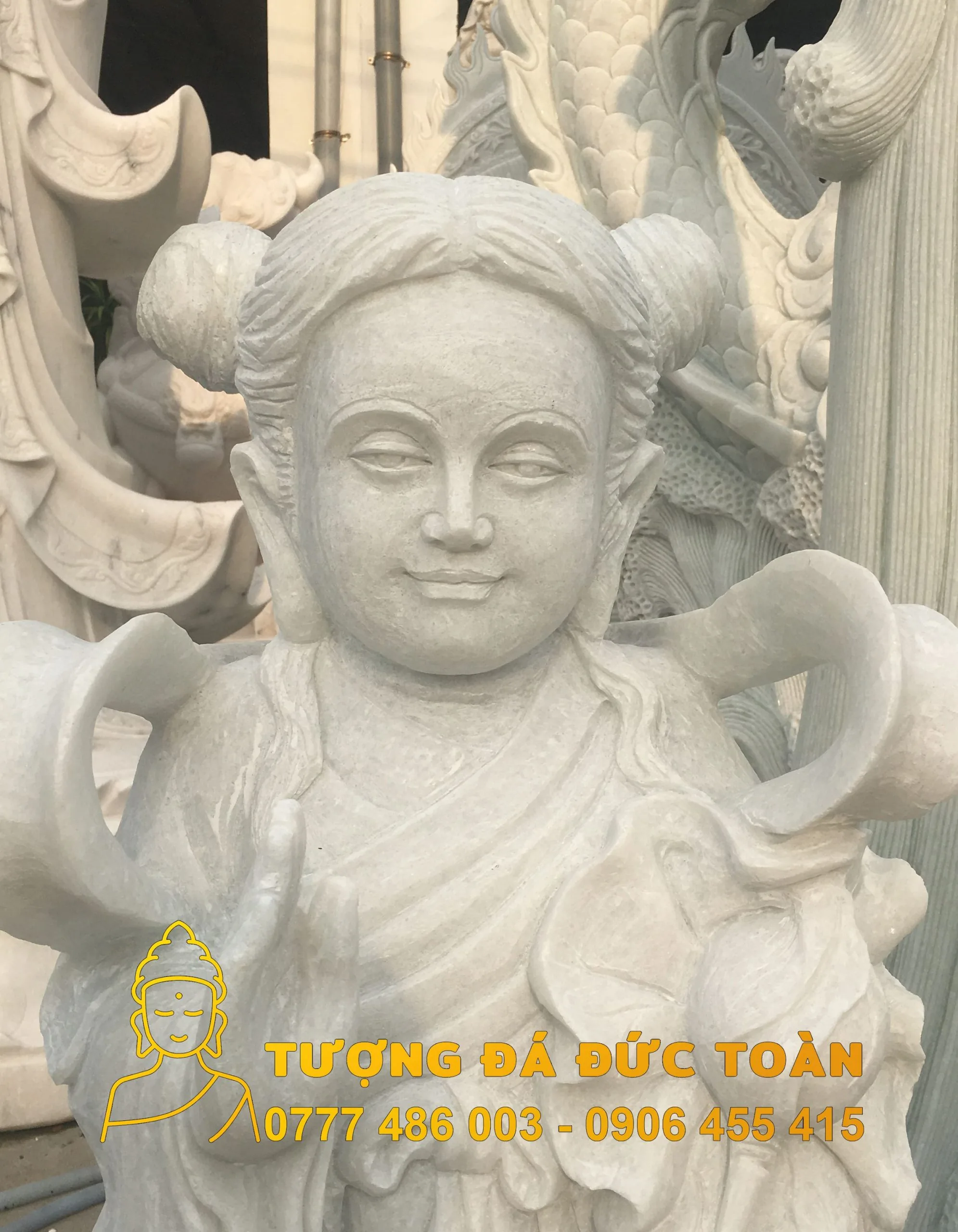 Tượng Tượng Thiện Tài Đồng Tử đá đẹp Đức Toàn màu trắng trước một cửa hàng.