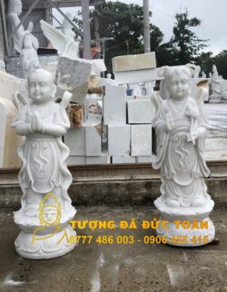 Hai bức tượng Tượng Tiên Đồng Ngọc Nữ đá non nước đẹp tuyệt đẹp trước một đống đá.