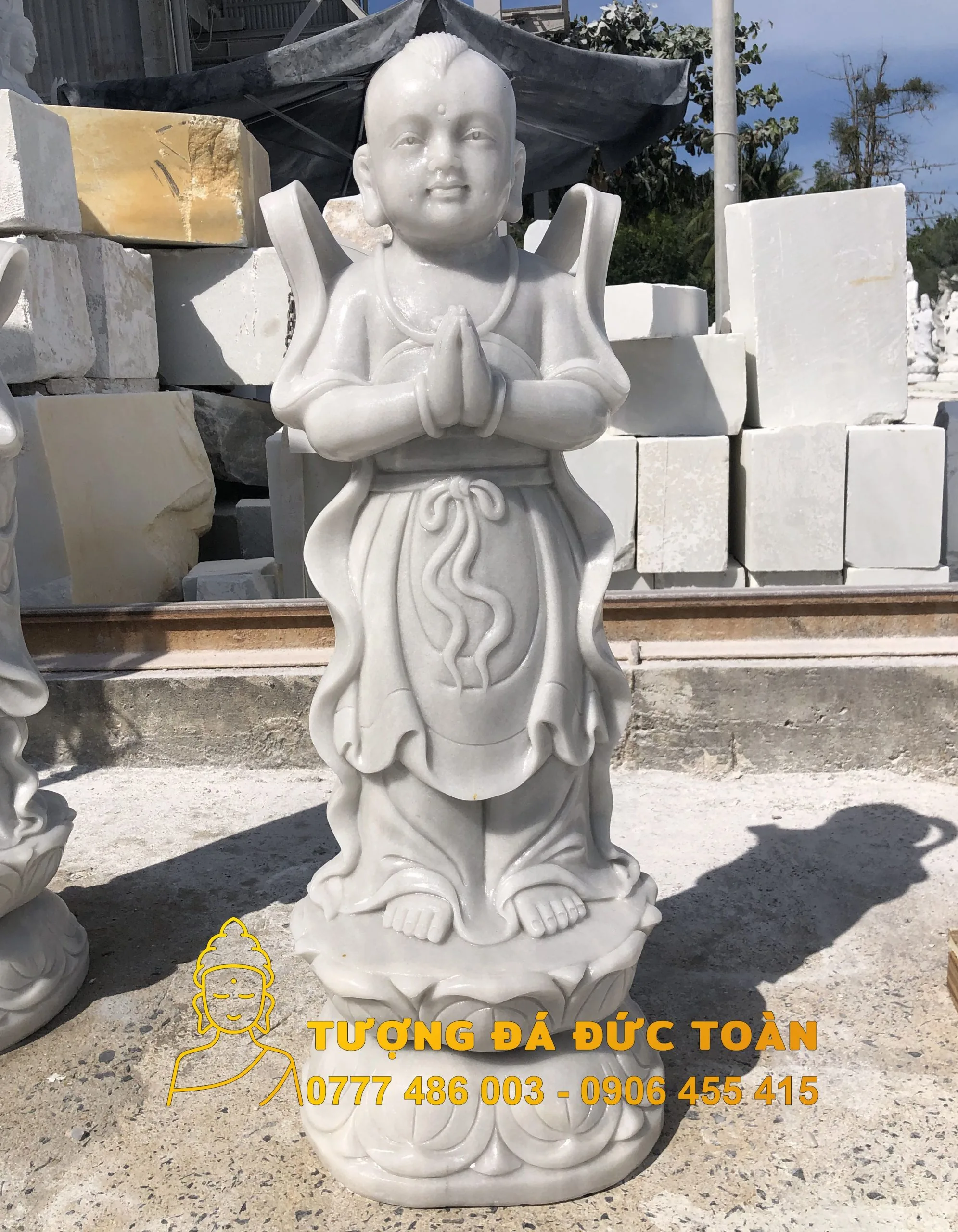 Tượng đá tự nhiên Thiện Tài Đồng Tử màu trắng ngồi trên đống đá.