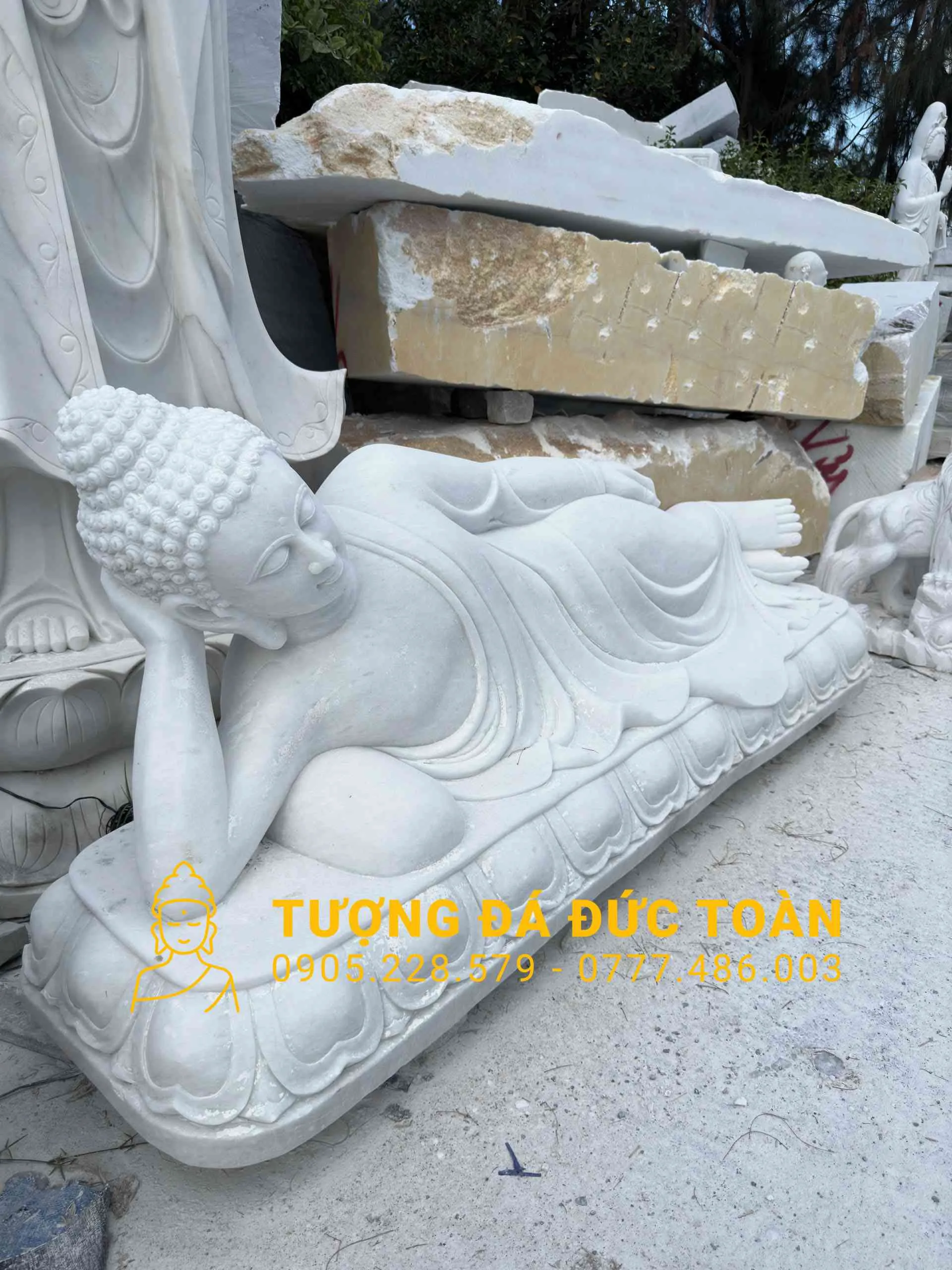 Một TƯỢNG PHẬT NHẬP NIẾT BÀN ĐÁ ĐẸP màu trắng nằm trên mặt đất.