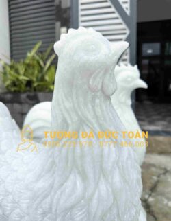 Hai bức tượng gà trống màu trắng trước một tòa nhà.