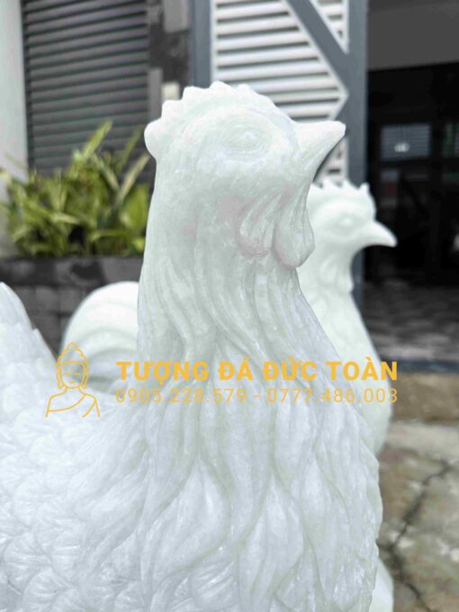 Hai bức tượng gà trống màu trắng trước một tòa nhà.