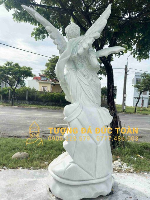 Bức tượng thiên thần màu trắng trước đường phố.