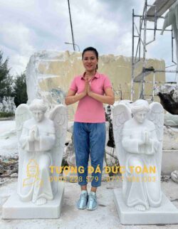 Một người phụ nữ đang đứng cạnh ba bức tượng trắng.