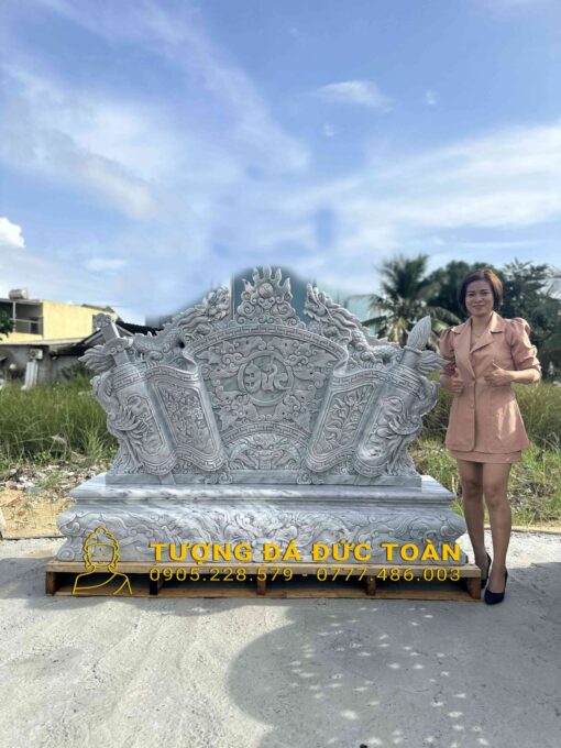 Một người phụ nữ đứng trước bức tượng lớn bằng đá cẩm thạch.