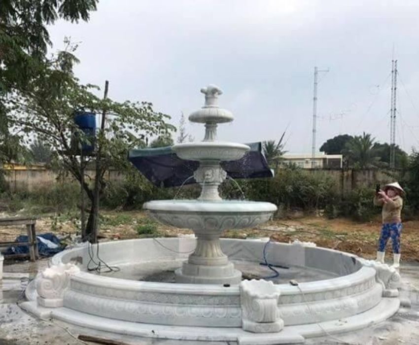 Một người đàn ông đang làm việc trên một đài phun nước trong sân.