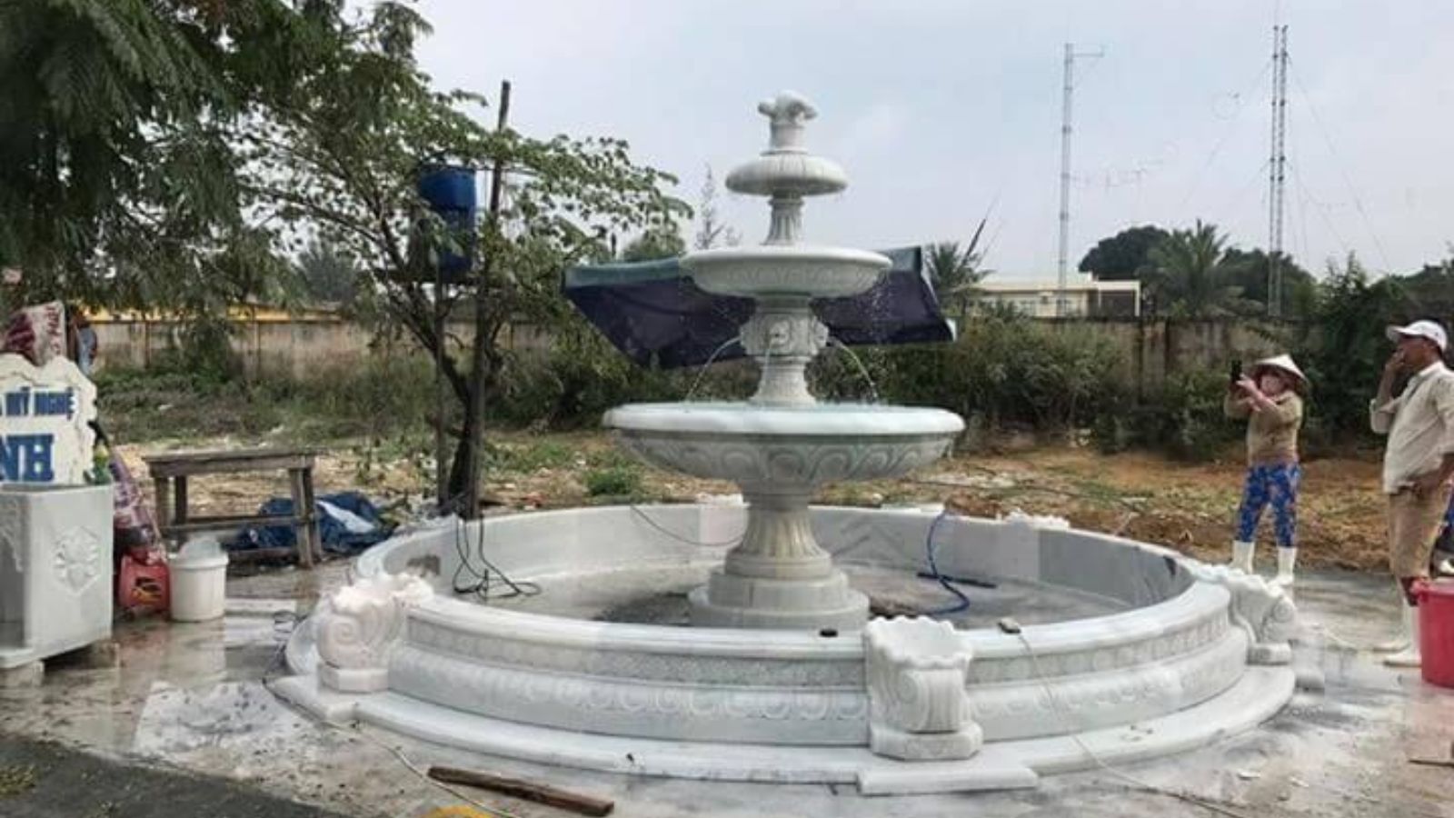 Một người đàn ông đang làm việc tại đài phun nước trước một tòa nhà.