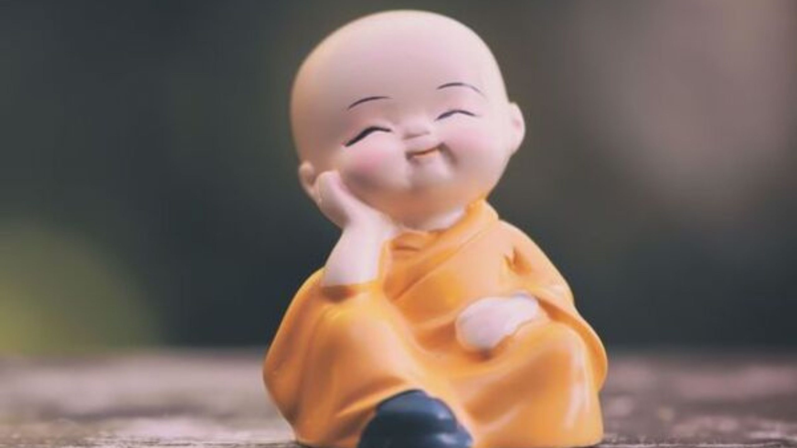 Một bức tượng chú tiểu ngồi trên bàn gỗ.