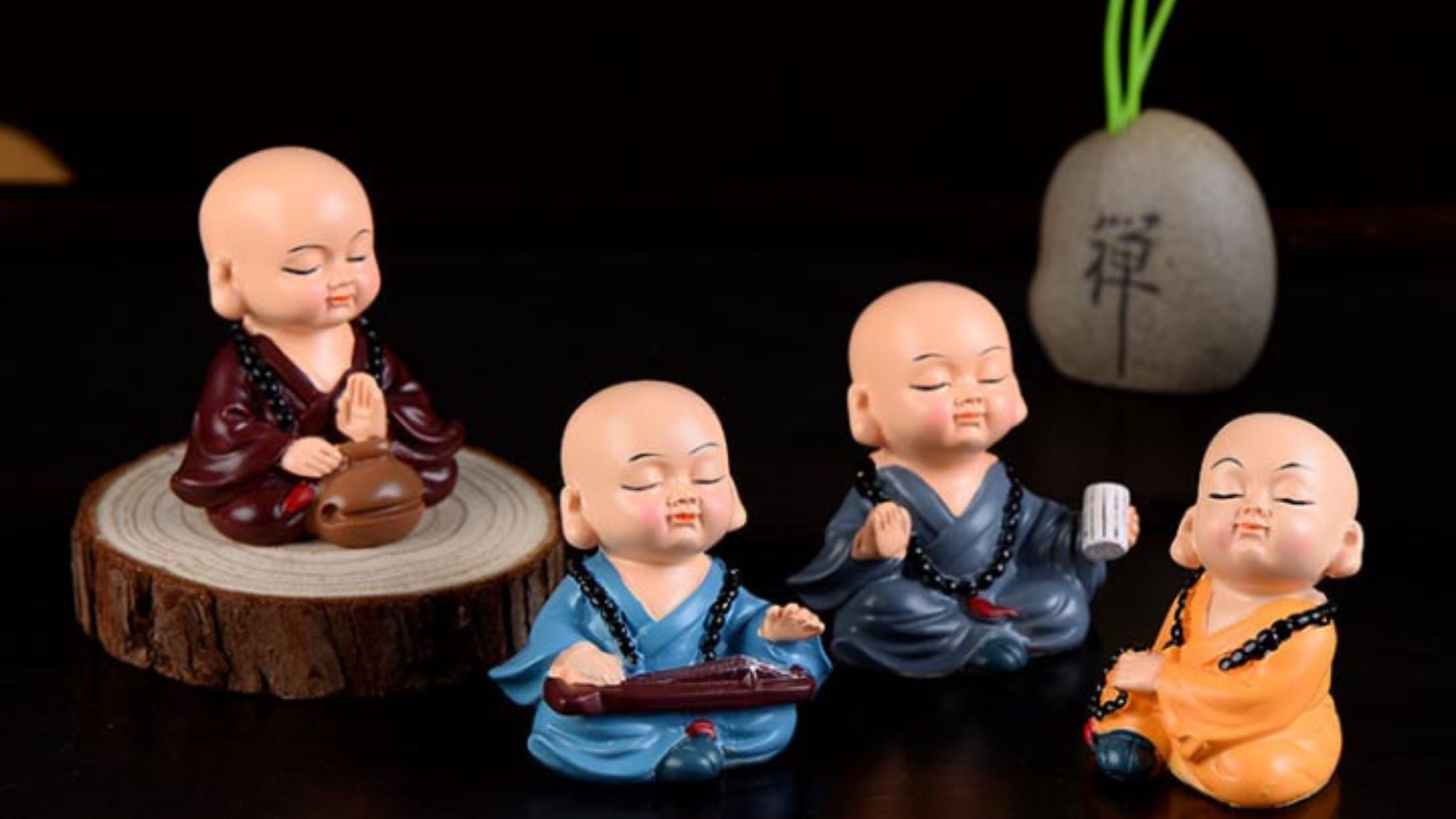 Bốn chú tiểu tượng hòa thượng ngồi trên gốc cây gỗ.
